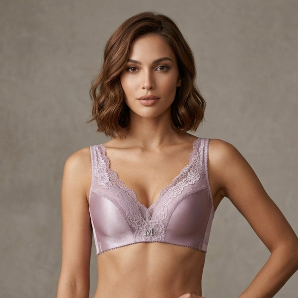 A woman modeling a light lavender satin bra and matching high-waisted briefs against a textured gray studio background.