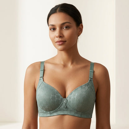 A woman modeling a sage green lace underwire bra against a warm, minimalist beige background.