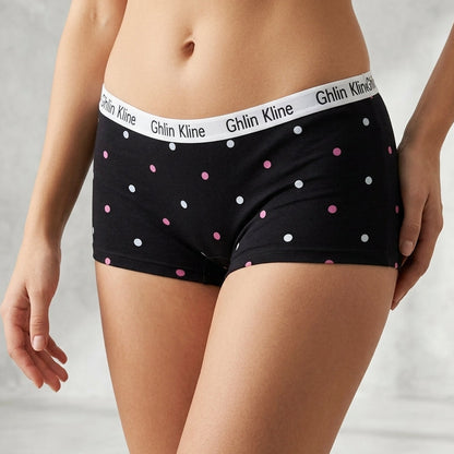 A model wearing black low-rise briefs with pink, white, and black polka dots and a white waistband printed with the brand name 'Ghlin Kline'.