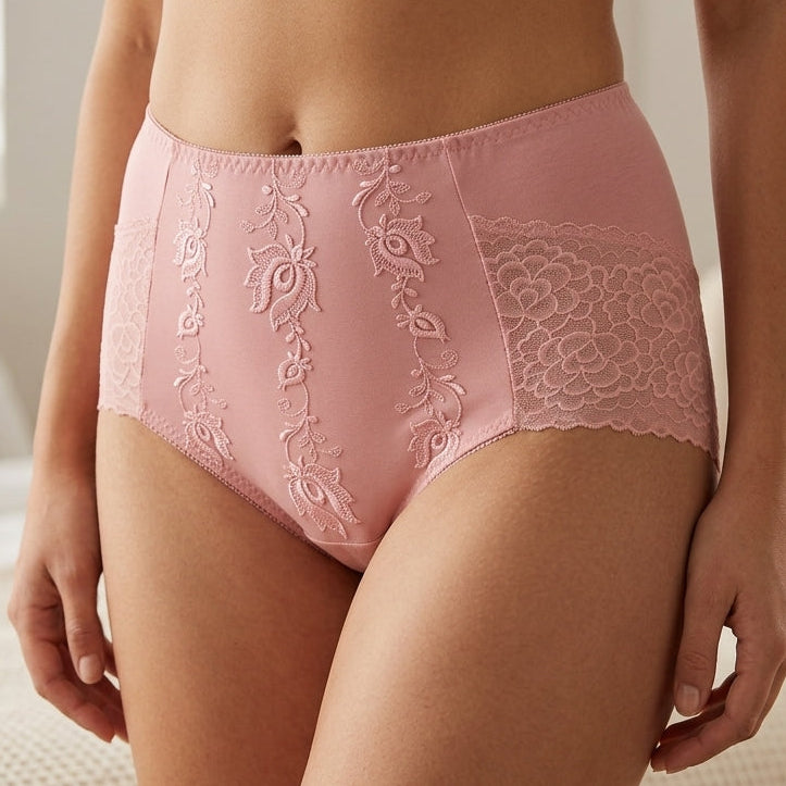 A model wearing high-waisted pink lace underwear, photographed from the waist to upper thighs in a softly lit bedroom setting.